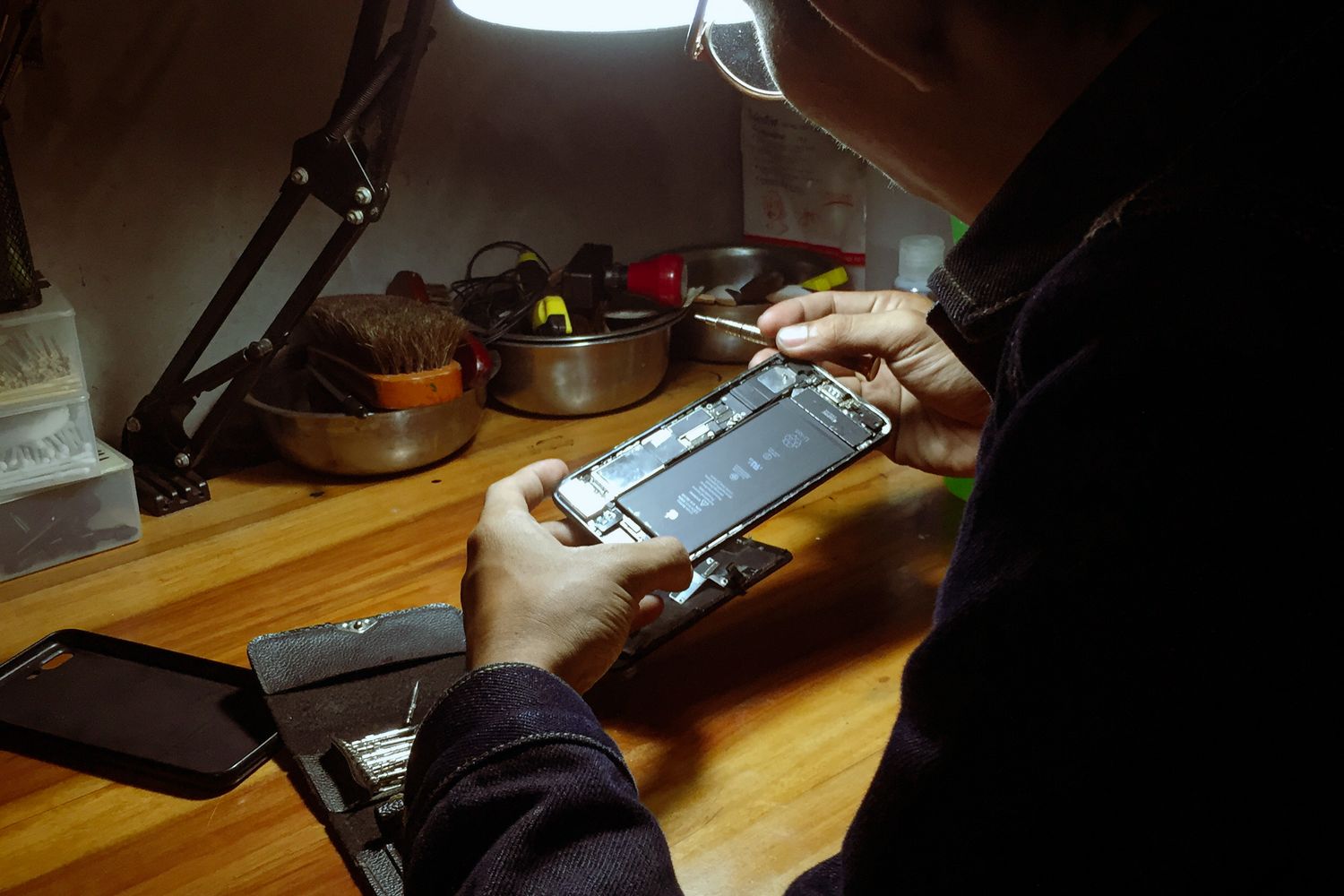 Técnico a reparar um telemóvel sob um candeeiro de secretária