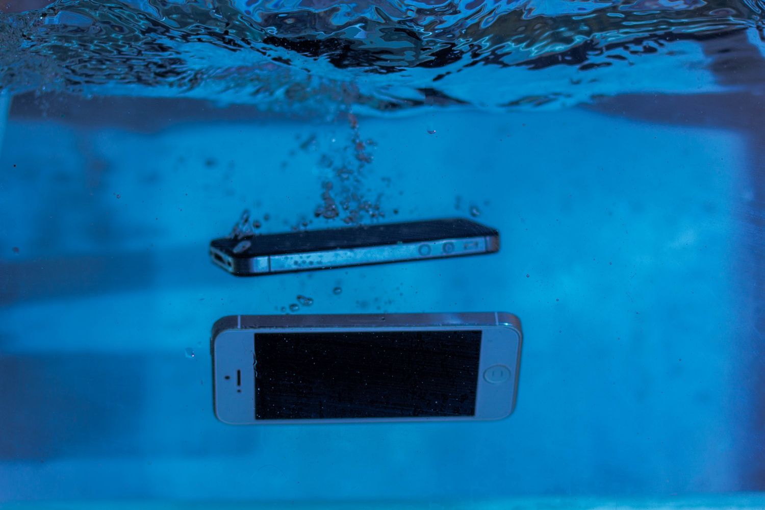 Telemóveis submersos em água com bolhas de ar à volta