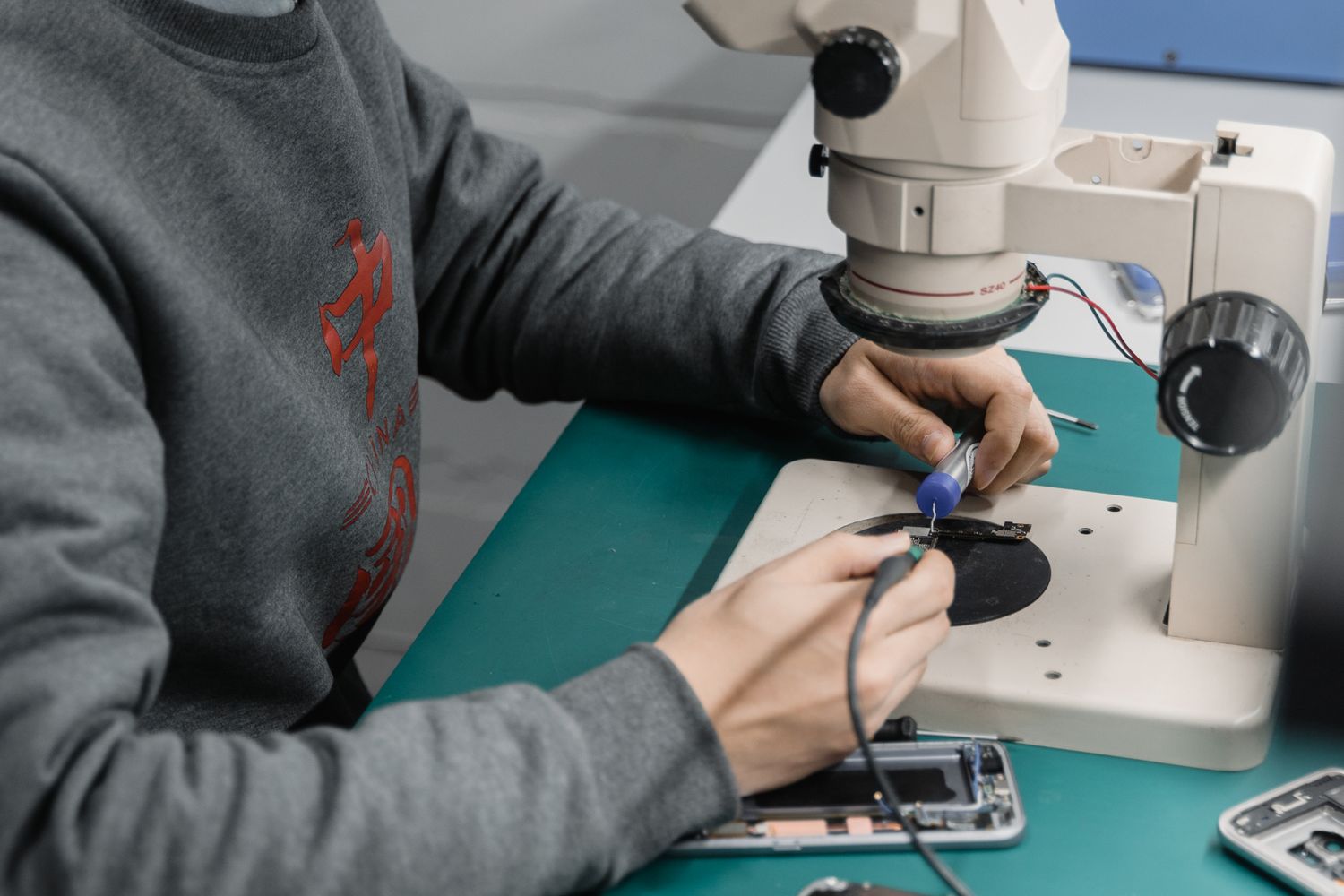 Técnico a inspecionar uma placa de circuito ao microscópio