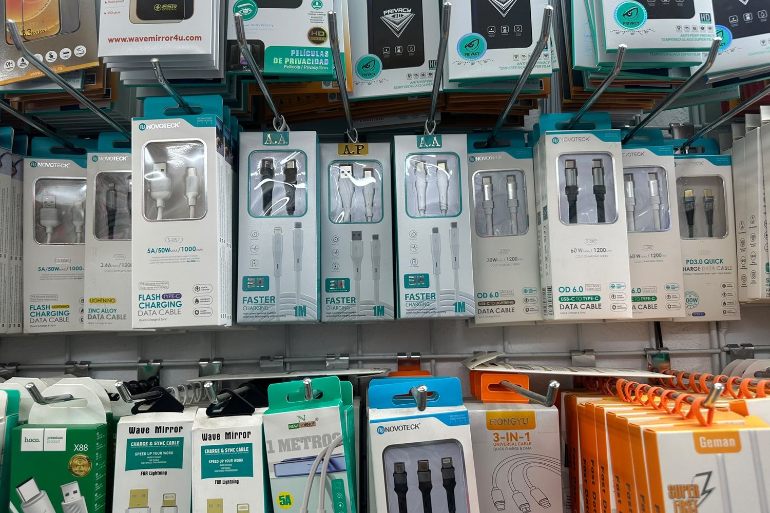 Cabos USB-C, Lightning e microUSB pendurados no expositor da loja