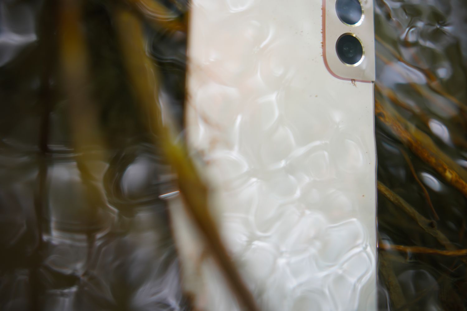 Telemóvel parcialmente submerso em água com ondulação à superfície